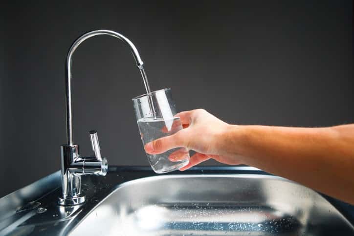 hand pouring a glass from water filter tap, close-up view