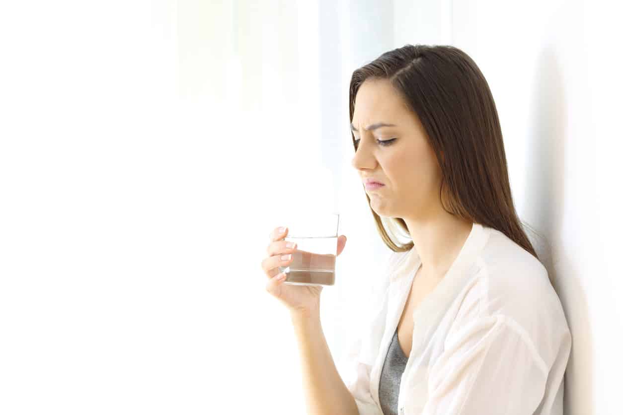 Disgusted woman drinking water with bad taste