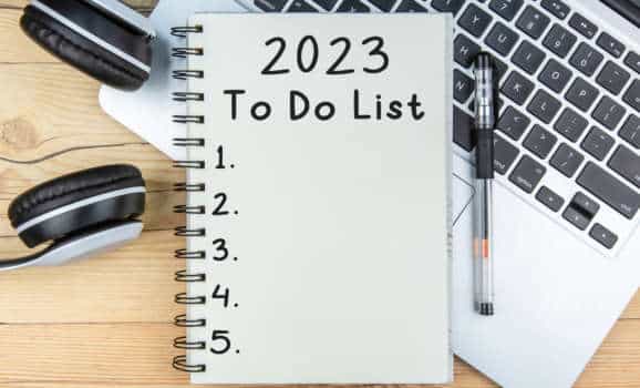 To Do List 2023 text on notepad with laptop and a earphone on wooden background