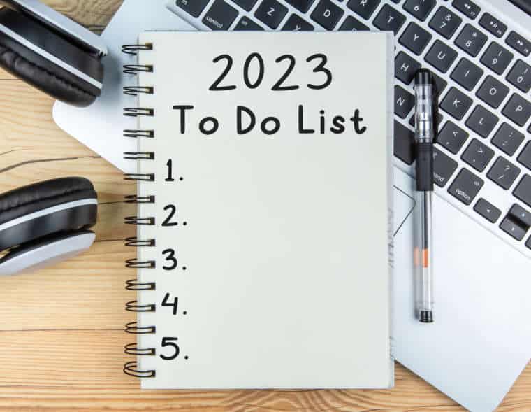 To Do List 2023 text on notepad with laptop and a earphone on wooden background