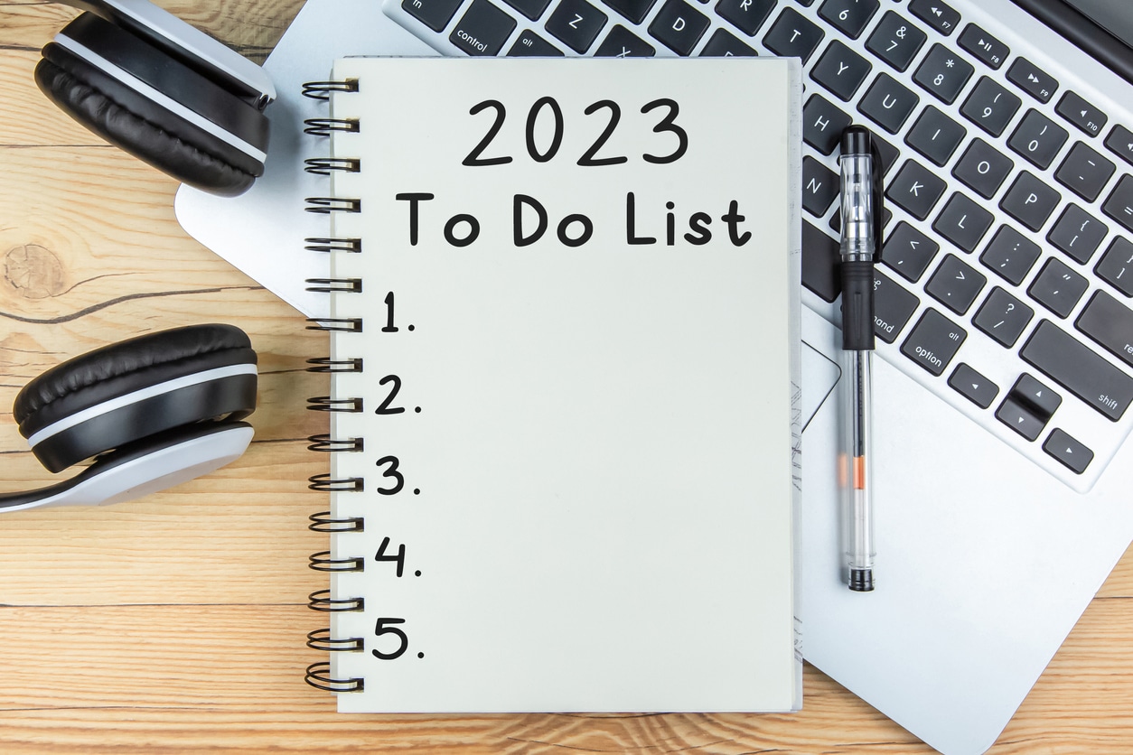 To Do List 2023 text on notepad with laptop and a earphone on wooden background