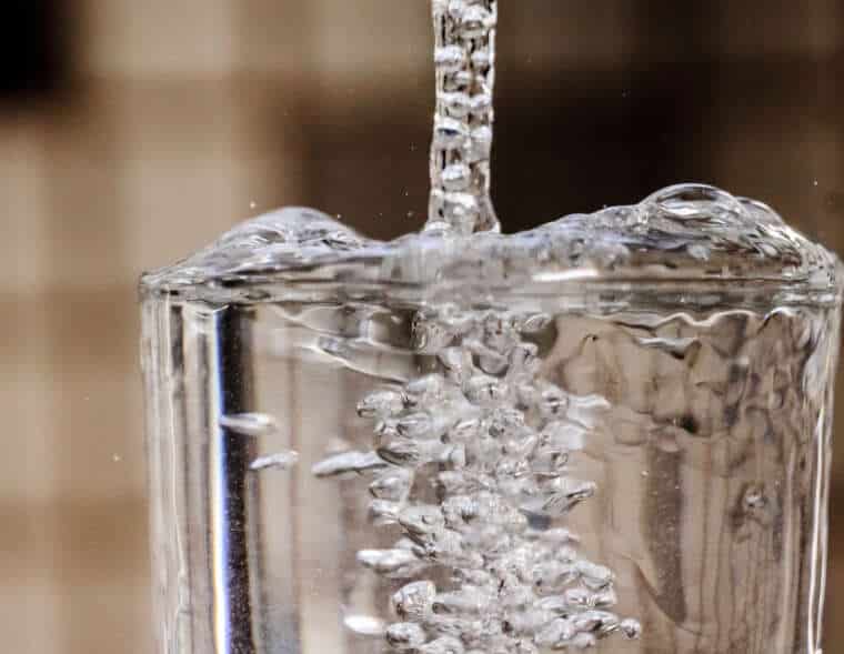 Drops of water falling into an empty glass.