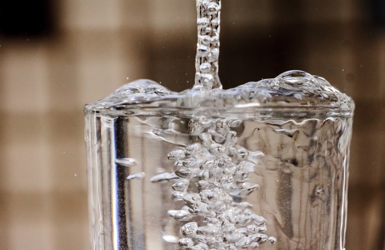 Drops of water falling into an empty glass.