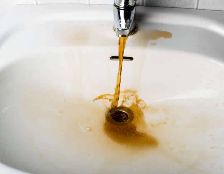 Dirty brown water running into a sink