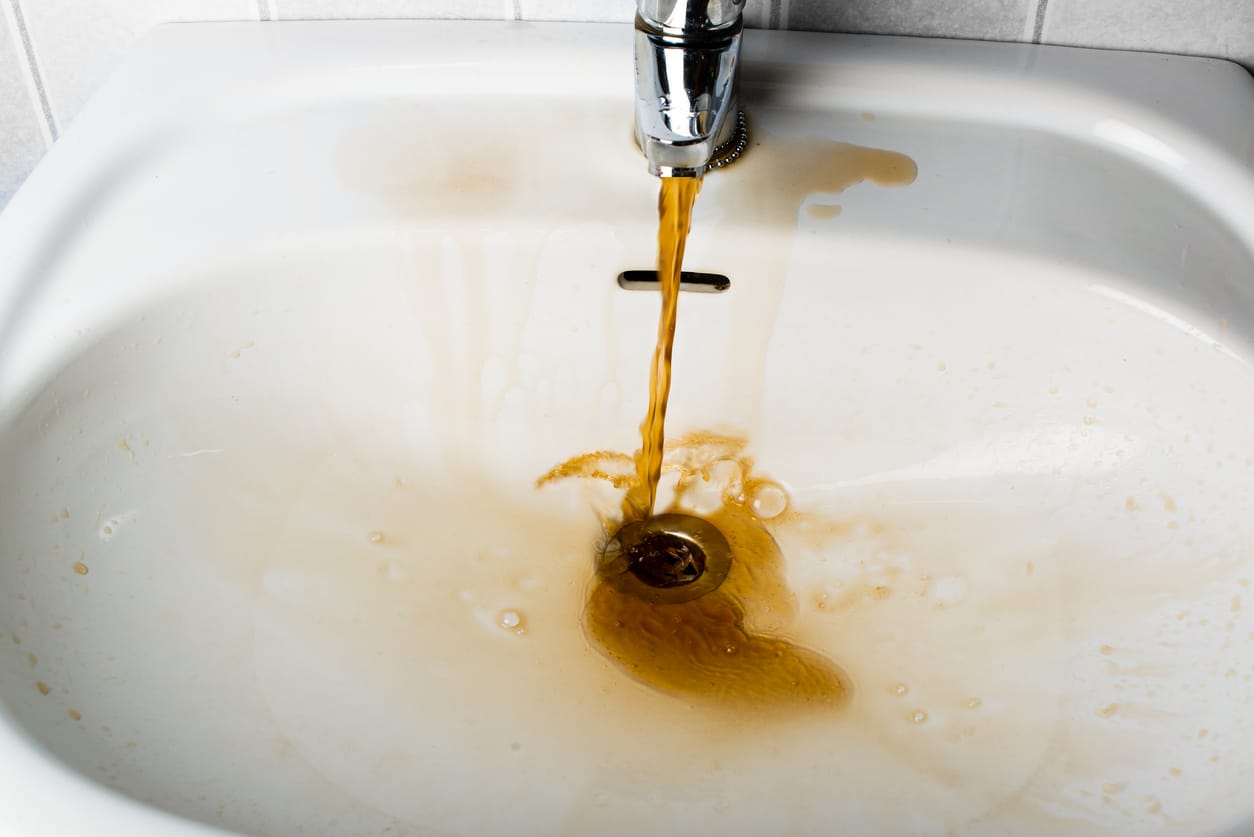 Dirty brown water running into a sink