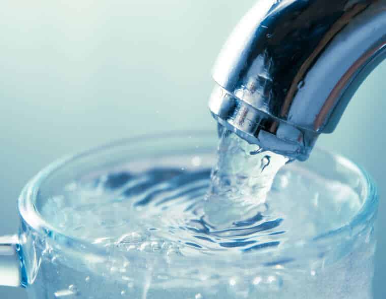 close-up view of water flowing from tap into glass