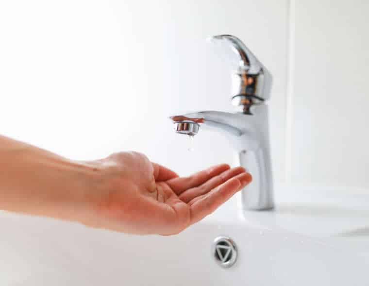 hand under faucet without water, one drop, close-up view