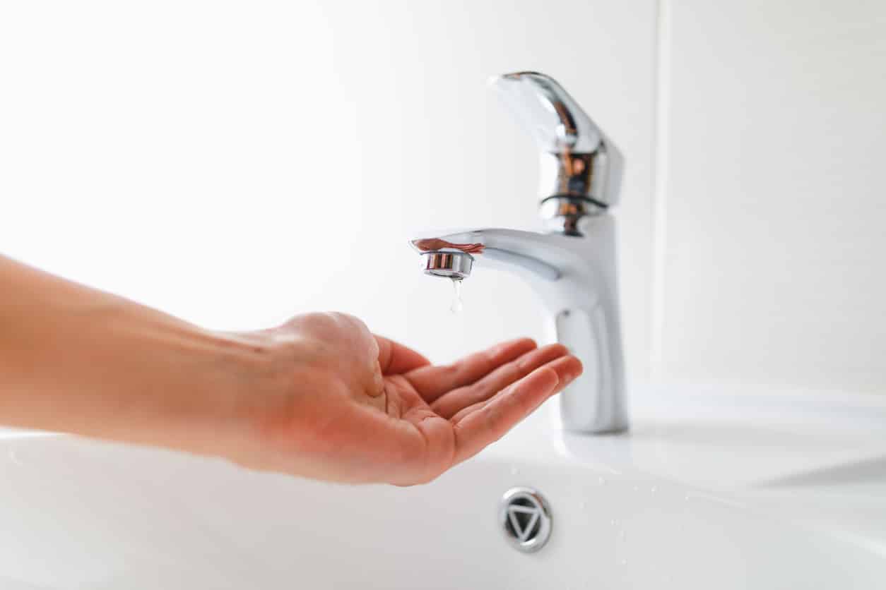 hand under faucet without water, one drop, close-up view