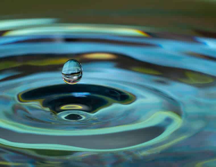 water drop falling and impacting on a body of water close up