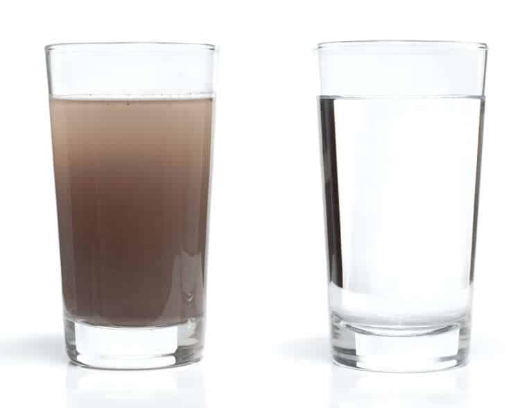 Two water glasses. One with dirty water and the other with fresh, clean water.