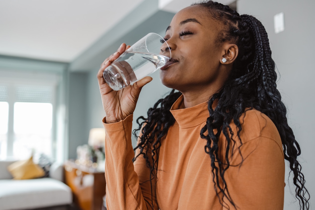 Shot of a beautiful woman drinking a glass of water at home