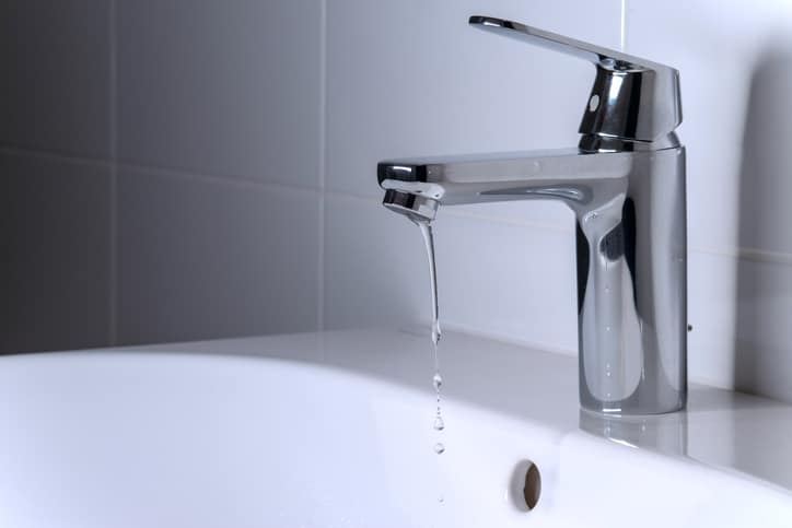 A weak stream of clean water pours from the tap into the sink.