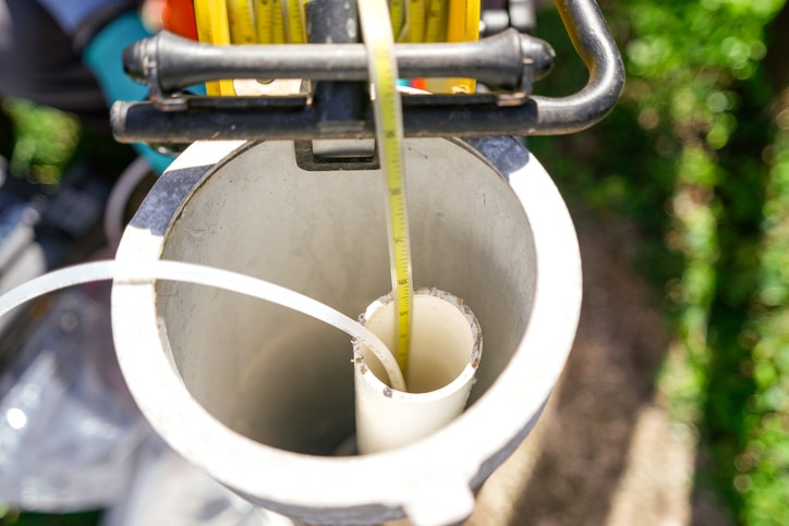Environmental scientist measuring depth to water inside a groundwater monitoring well.